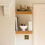 A set of 3 faux figs placed in a bowl on a shelf
