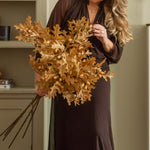 Woman arranging Charles Ted Faux Oak Leaves with Acorns beside a fireplace
