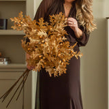 Woman arranging Charles Ted Faux Oak Leaves with Acorns beside a fireplace