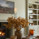 Charles Ted Faux Oak Leaves with Acorns styled in a rustic vase on a coffee table