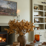 Charles Ted Faux Oak Leaves with Acorns styled in a rustic vase on a coffee table