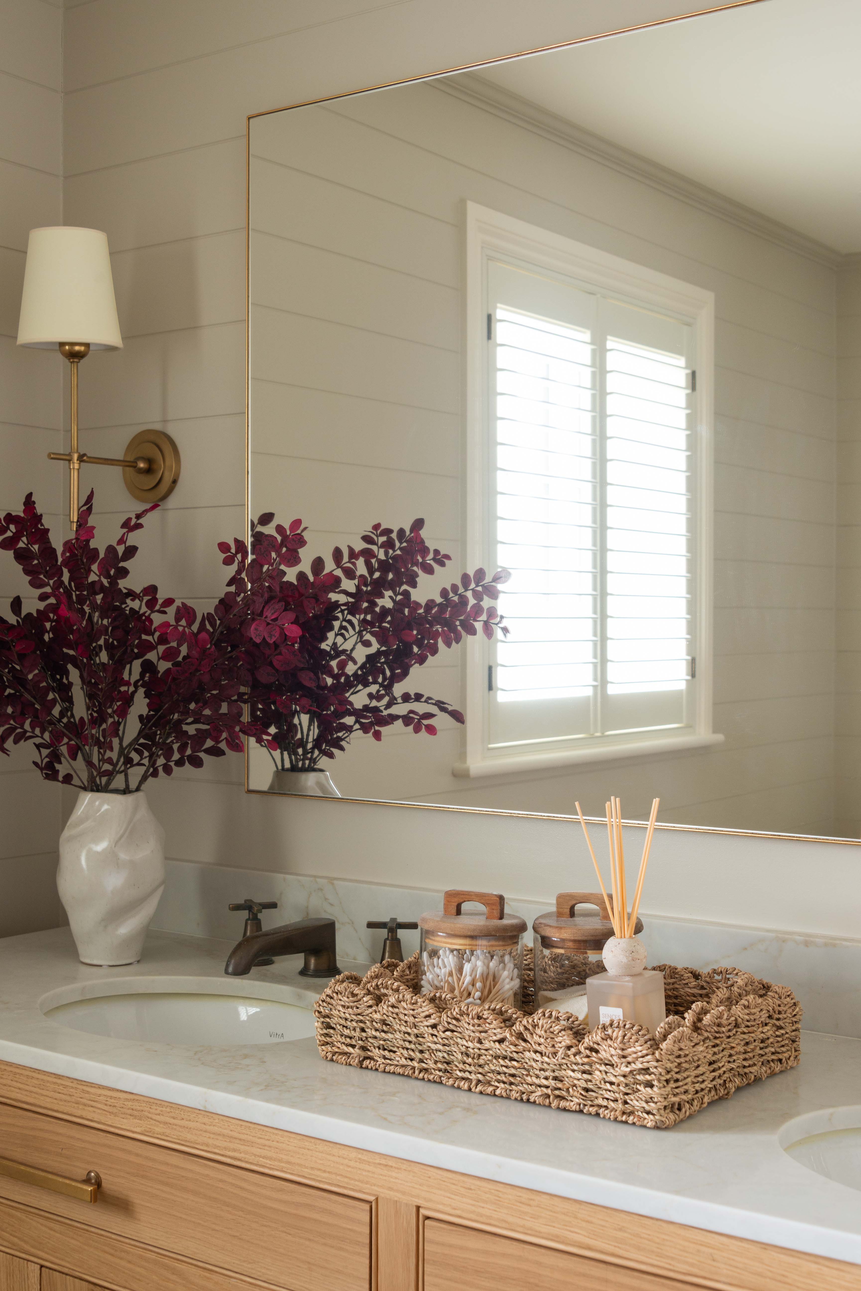 Bathroom vanity with a mirror, sink, and decorative items.