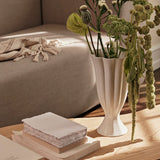 The Ivory Flute Ceramic Vase features a tall, elegant silhouette reminiscent of a blooming tulip. Crafted from high-quality ceramic, its glossy white glaze highlights the fluted vertical ridges that cascade gracefully from the scalloped rim to the flared base. This timeless piece brings a touch of sophistication to any space, whether displayed as a standalone sculpture or filled with fresh florals. Perfect for modern, classic, or minimalist interiors.