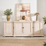 A white oak sideboard with four doors and bronze hardware, placed in a room with decorative items on top and a plant to the side.