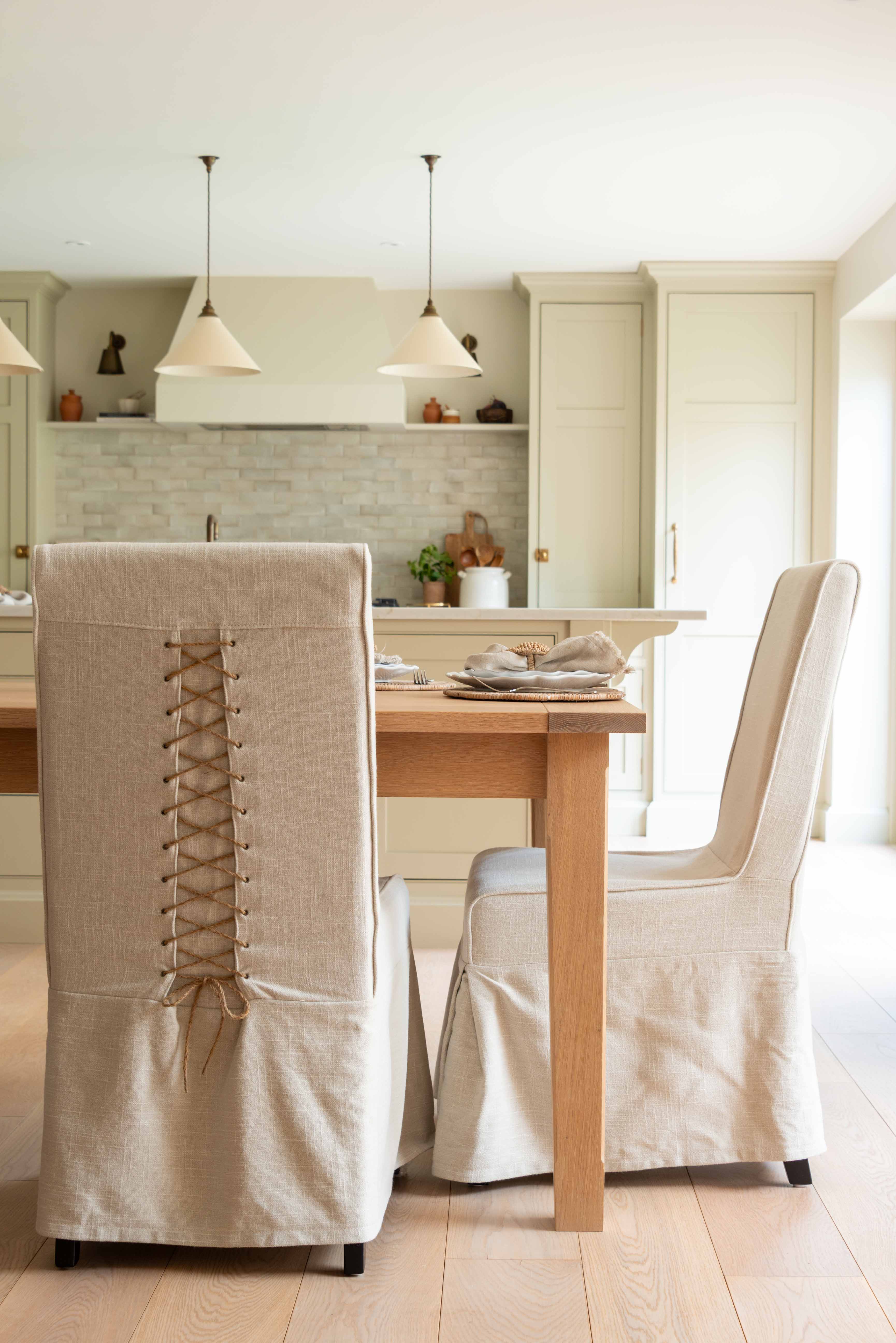 chair features a beautifully tailored loose linen slipcover in a natural beige hue, accented with a charming corset-style lace-up back for added visual interest and secure fit.