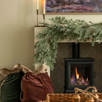 Charles Ted Noble Pine Garland with realistic pine branches and cones styled across a fireplace mantel