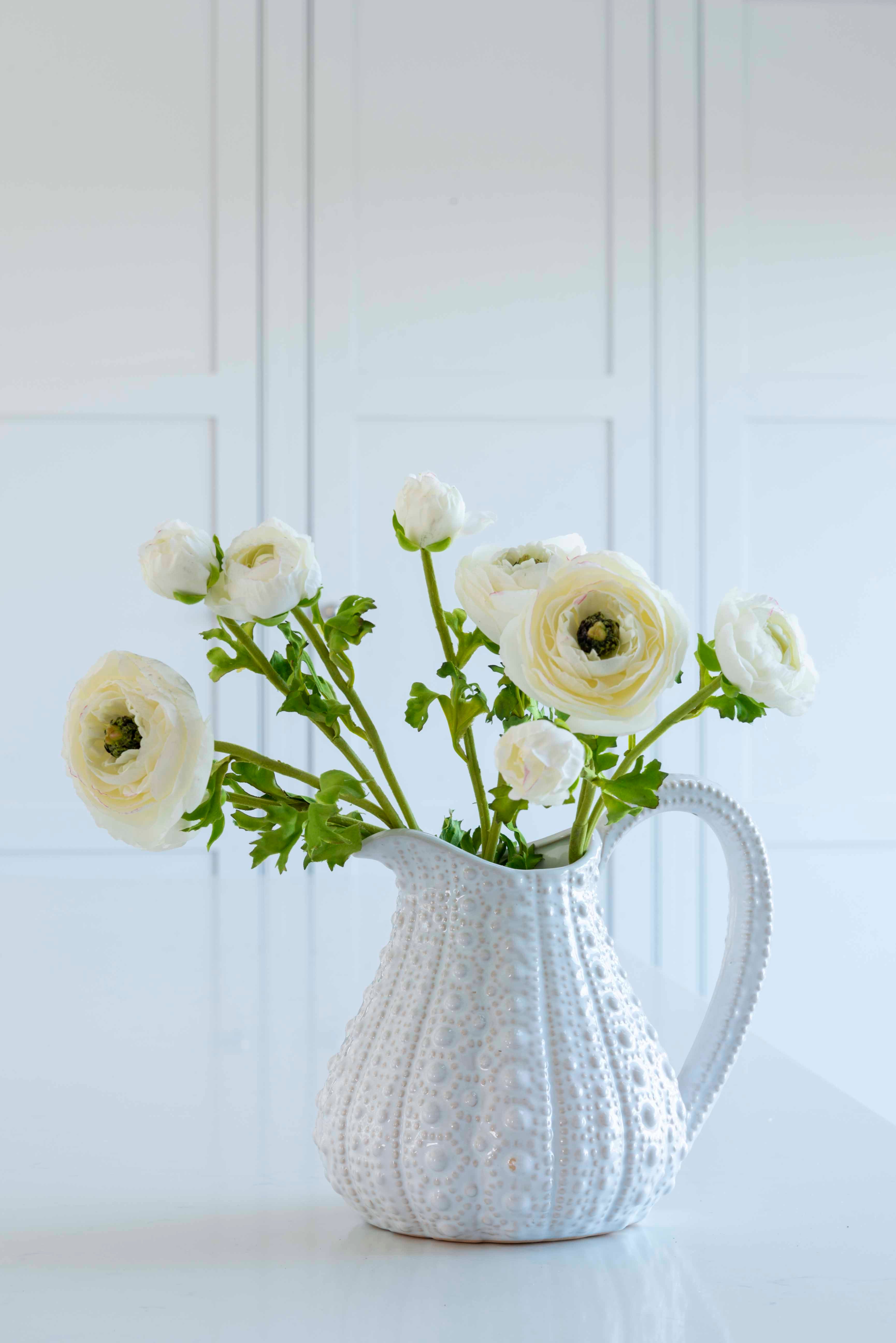 Charles Ted Ranunculus Spray Cream single stem with realistic layered cream blooms and green foliage arranged in a jug