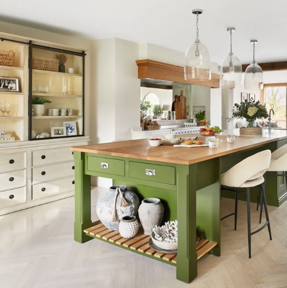 Kitchen with a green island and wooden countertop, featuring various kitchen items and decor.