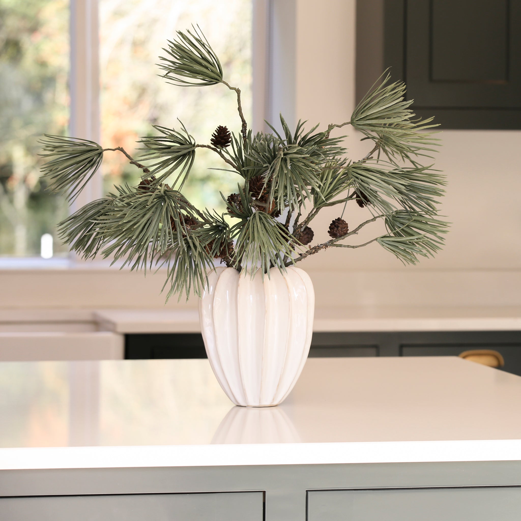 Charles Ted Scot's Pine Cone Spray with long pine needles and cones displayed in a white vase on a table