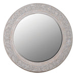 Round decorative mirror with intricate carvings on a white background