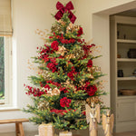 Decorated Christmas tree with red bows and ornaments in a living room.
