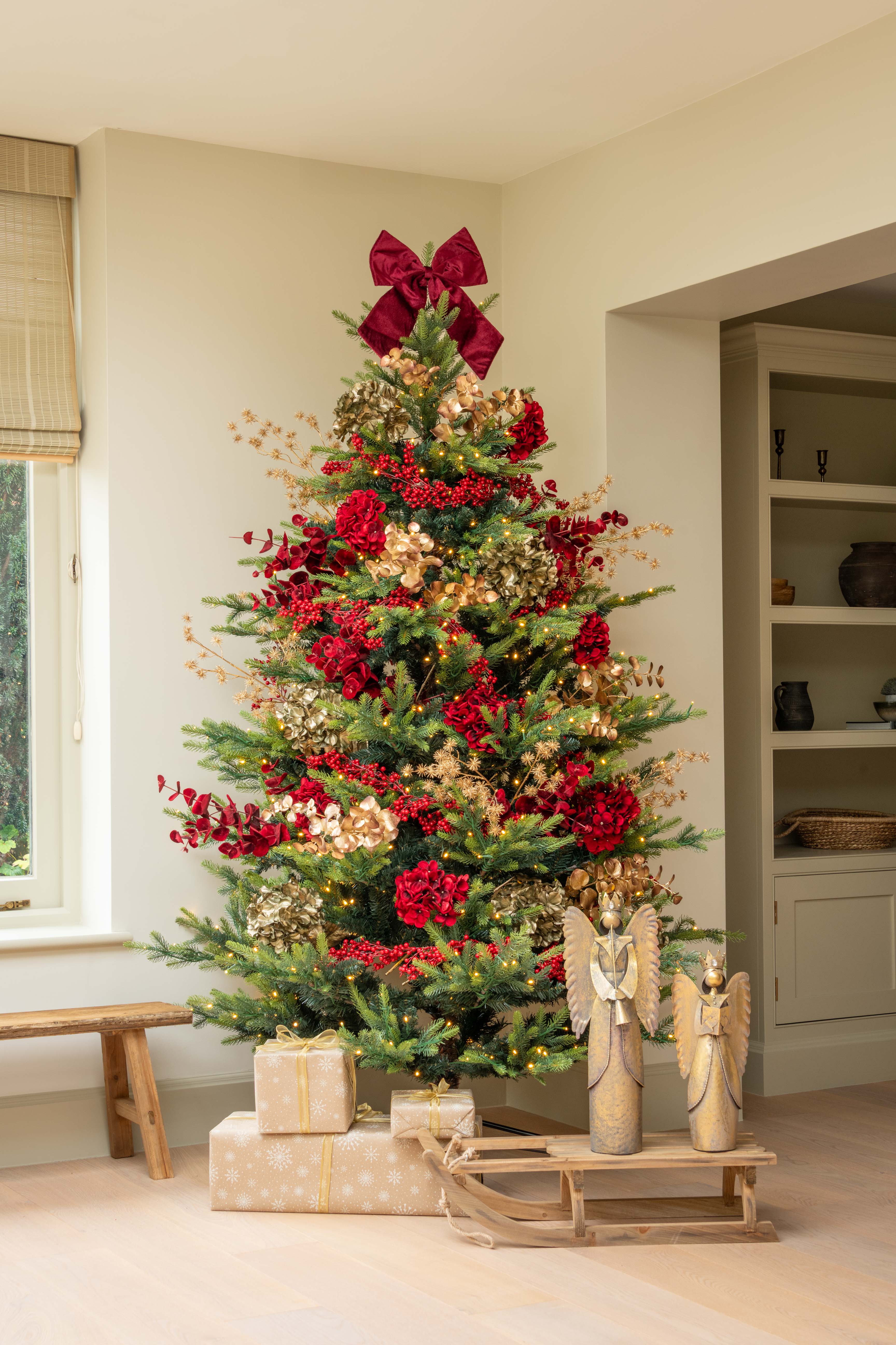 Decorated Christmas tree with red bows and ornaments in a living room.