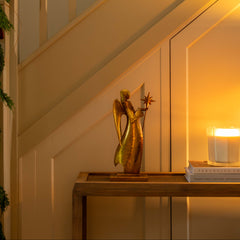 Decorative angel figure on a table with a candle next to a staircase