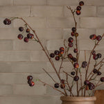 Beige vase with cherry branches on a kitchen counter with a tiled backsplash close up