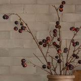 Beige vase with cherry branches on a kitchen counter with a tiled backsplash close up