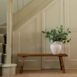 Staircase with a wooden bench and plant against a wall.
