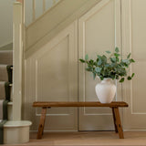 Staircase with a wooden bench and plant against a wall.