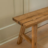 Wooden bench against a beige wall on a wooden floor