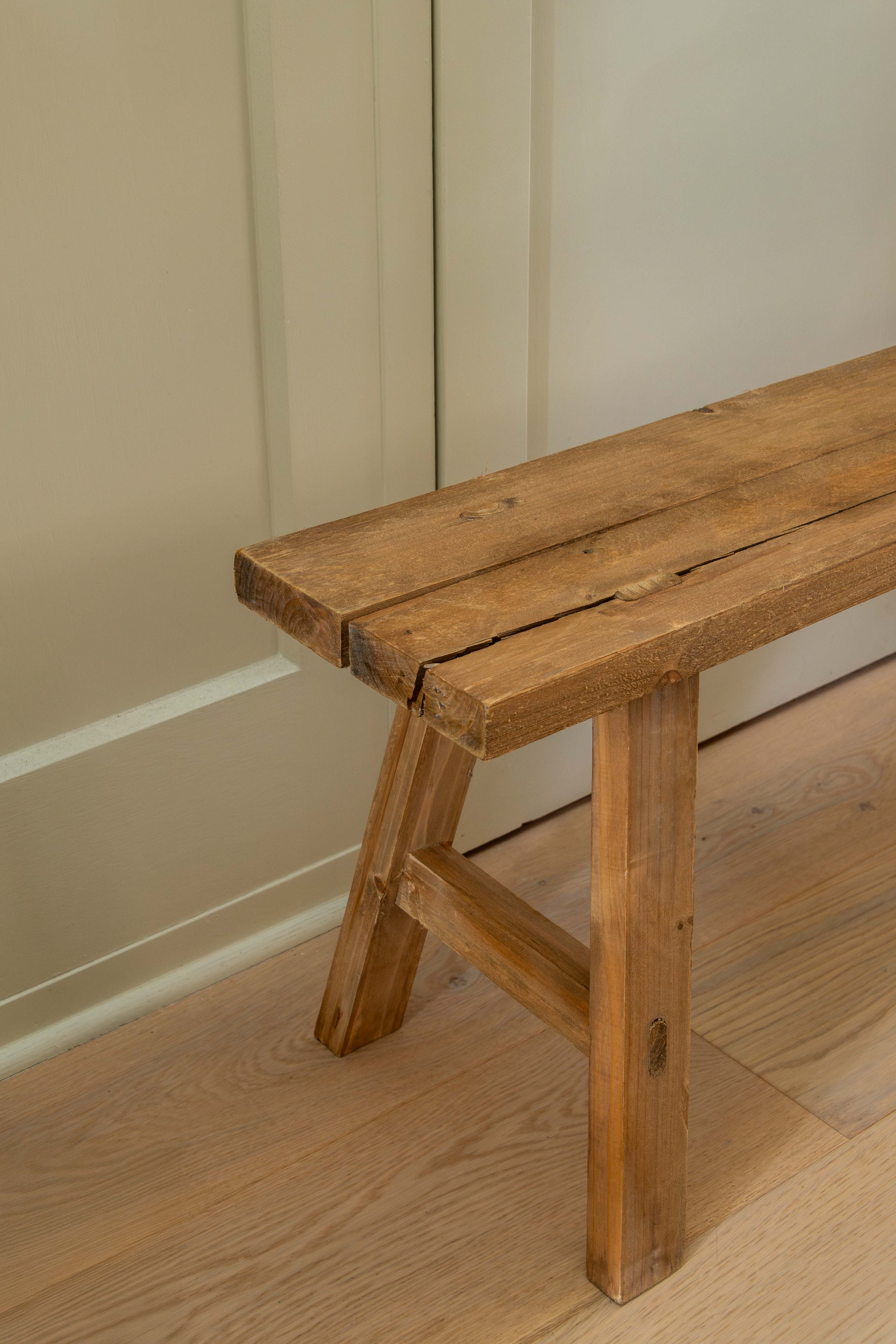 Wooden bench against a beige wall on a wooden floor