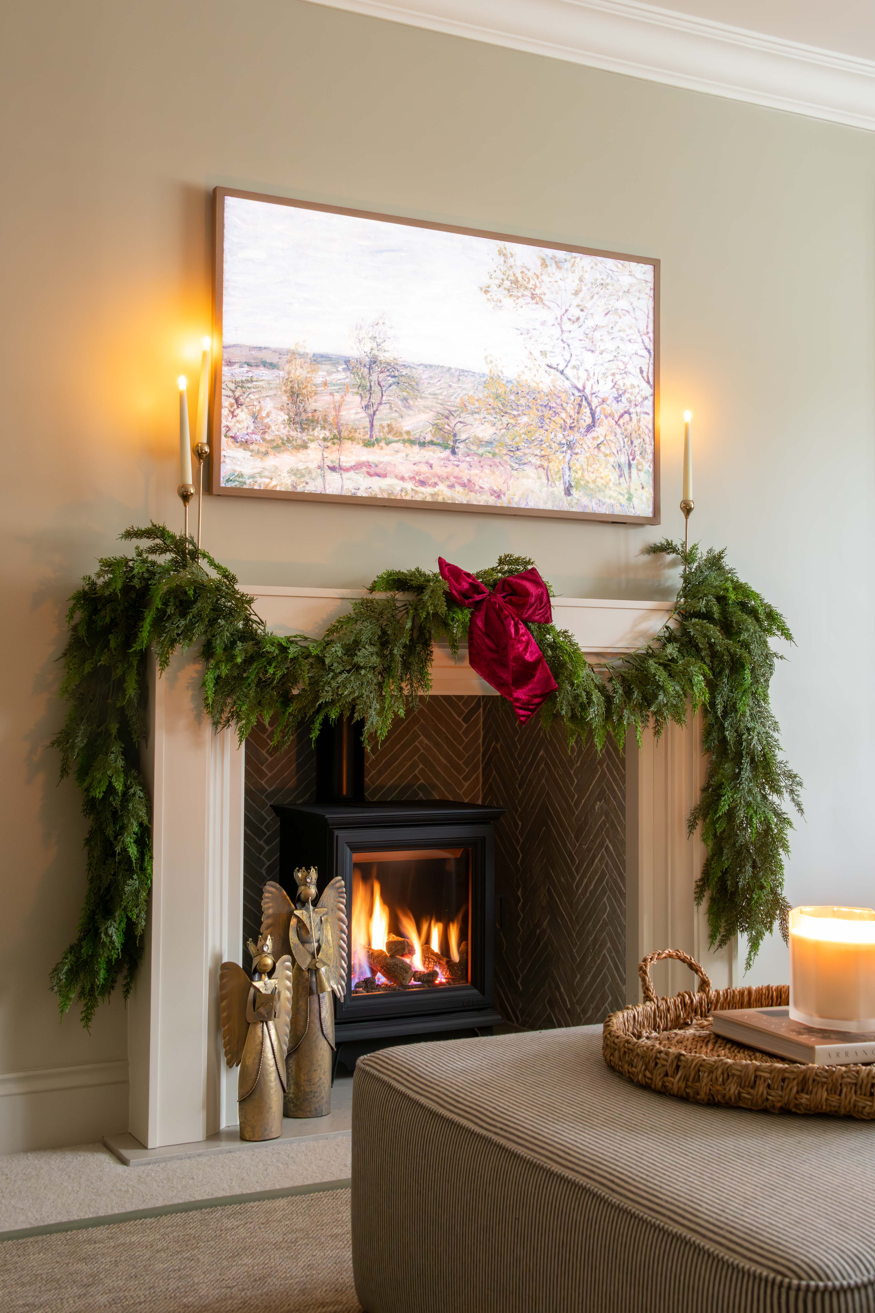 Living room with a fireplace decorated for Christmas, featuring greenery and a red bow.