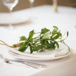 Faux Charles Ted Mistletoe Bundle with green leaves and white berries styled on a white plate at a festive table setting
