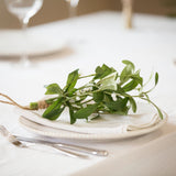Faux Charles Ted Mistletoe Bundle with green leaves and white berries styled on a white plate at a festive table setting