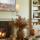 Brown faux fern stem styled in a rustic vase with warm autumn inspired decor