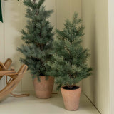Decorative setup with a wreath, gift boxes, and small trees inside a white cabinet.
