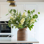 Faux white lilac stem with delicate blooms and green buds in a vase arrangement