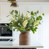 Faux white lilac stem with delicate blooms and green buds in a vase arrangement