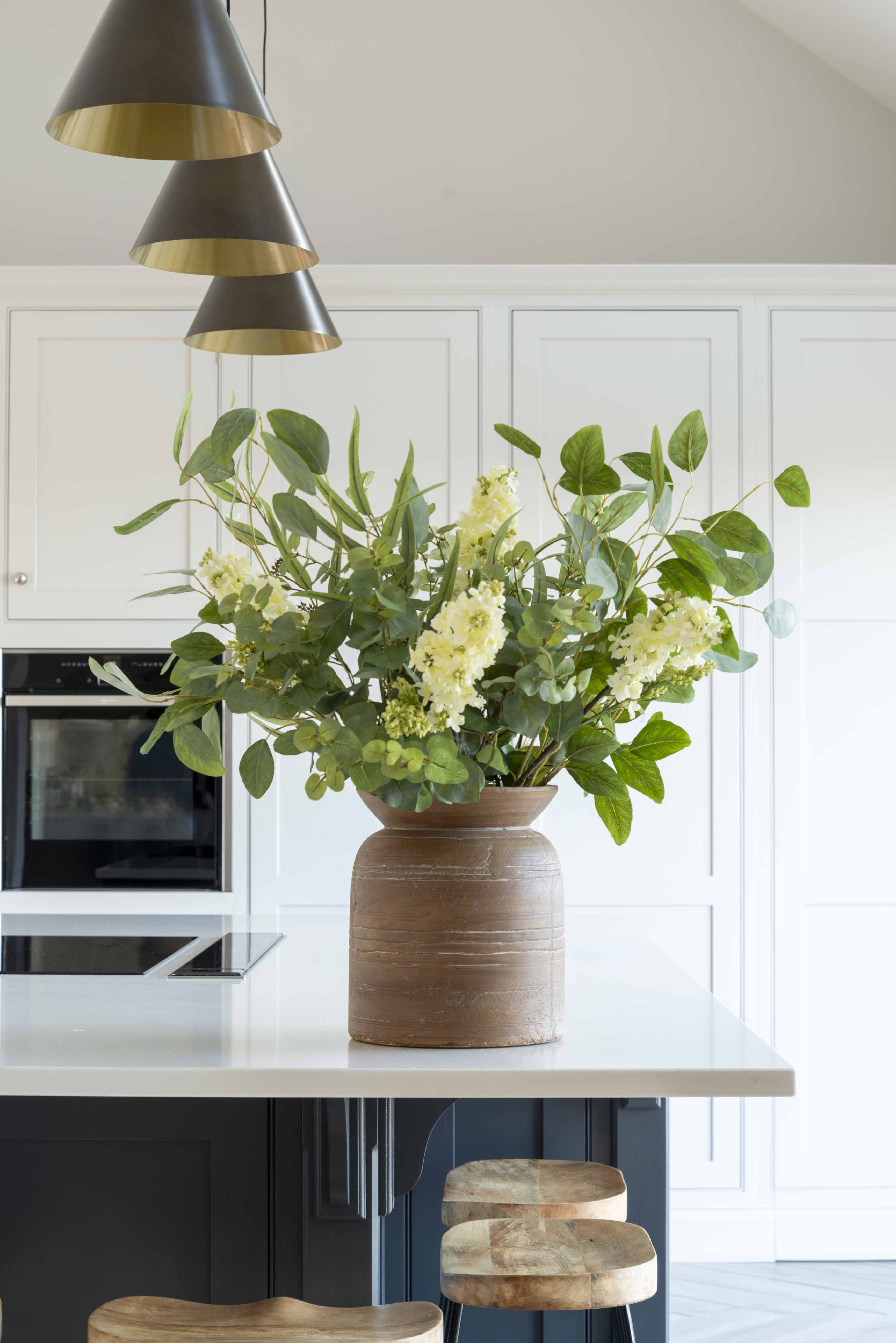 Faux white lilac stem with delicate blooms and green buds in a vase arrangement