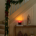 Decorative staircase with Christmas garland, candle, pinecones, and a trumpet.