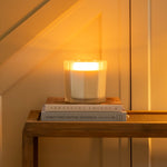 Candle on a small table under a staircase with warm lighting
