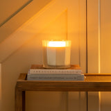Candle on a small table under a staircase with warm lighting