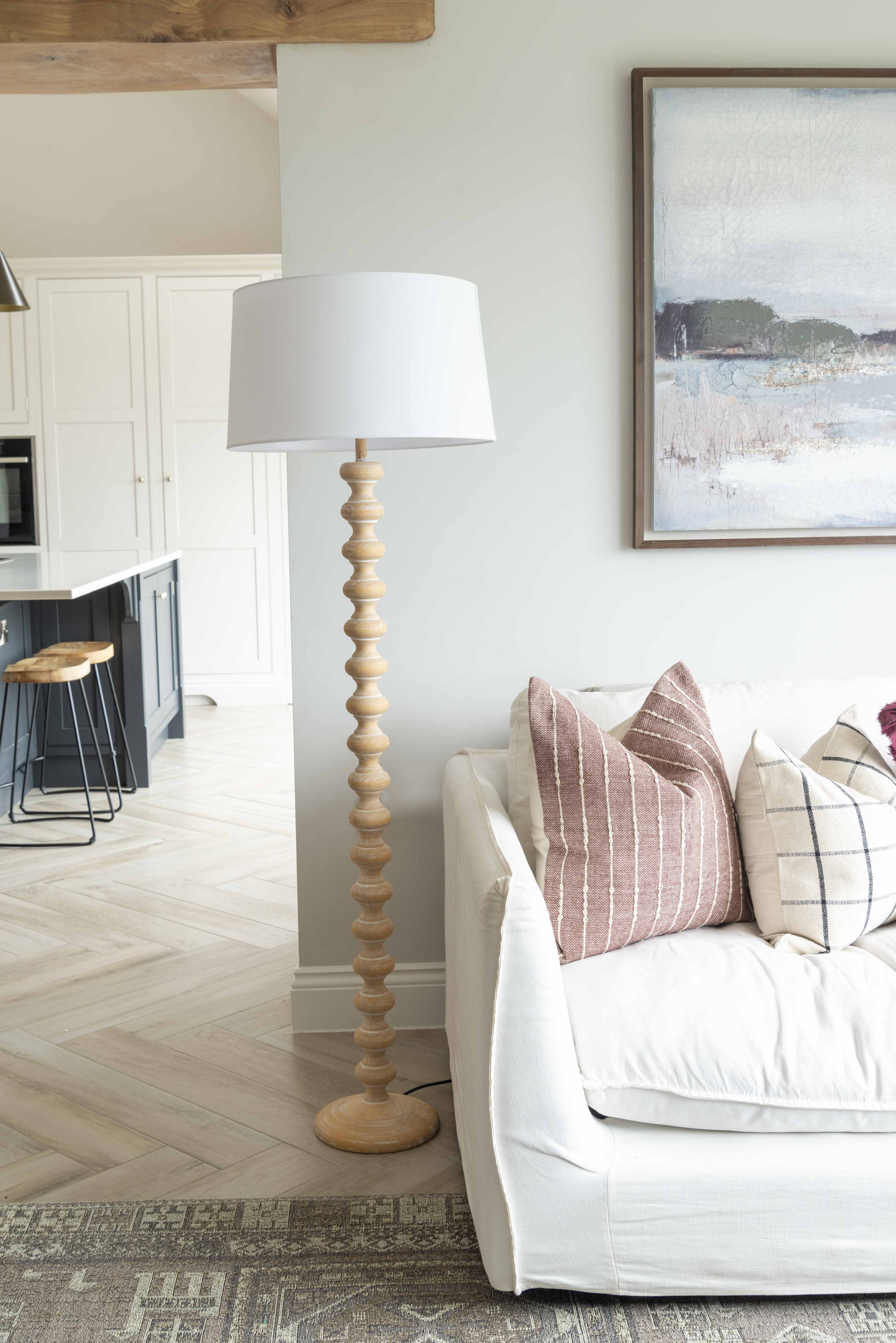 Georgia Floor Lamp with natural wood base beside cream sofa and decorative cushions