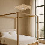 Wooden canopy bed in a bedroom with large windows and neutral decor.