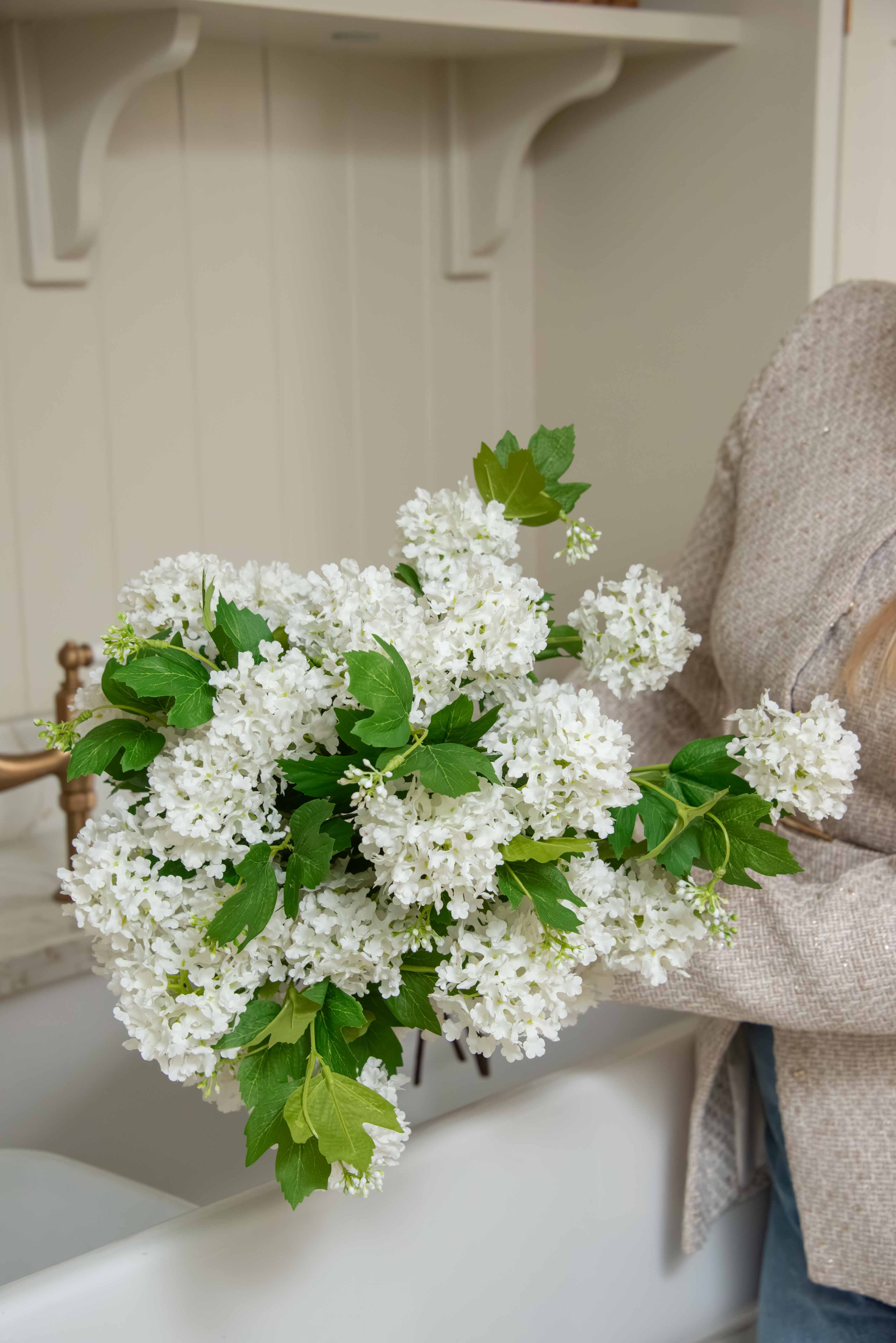 Pom Pom White Viburnum Spray. Its snowball-like floral heads and lush leaves, delicately drooping like the real thing, make for an incredibly lifelike addition to any setting. Use between 6 - 8 stems for a truly impressive impact.