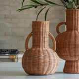 Two wicker vases with greenery on a kitchen counter