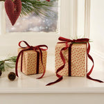 Two Christmas presents wrapped in patterned paper with red ribbons on a windowsill.