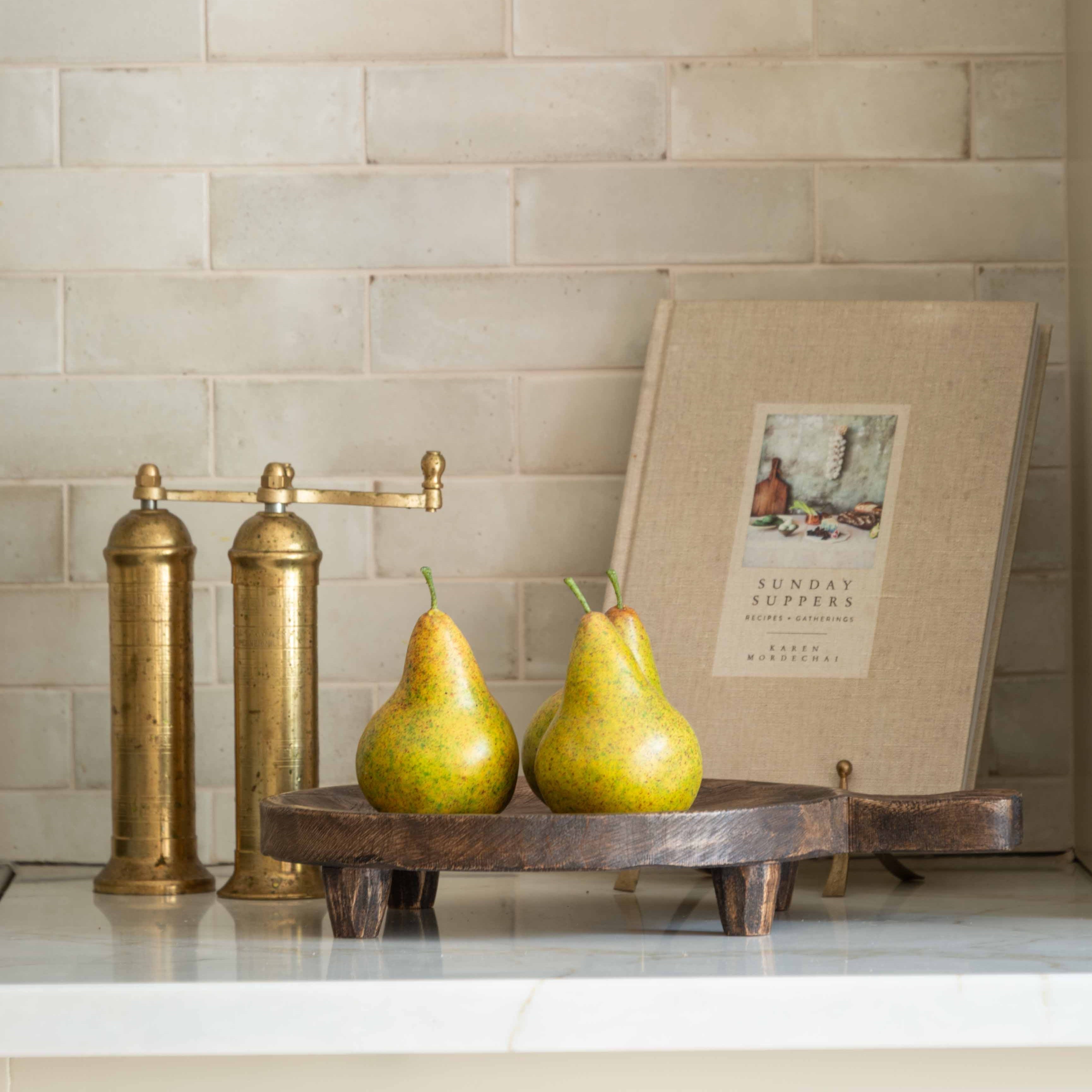 Rustic wooden footed tray styled with fresh pears on a marble countertop