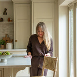 Woman standing in a kitchen next to a table with a bowl of fruit