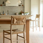 Kitchen with wooden table and chairs, light-colored cabinets, and a tiled backsplash.