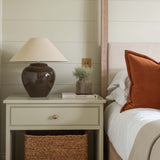 Bedroom with a nightstand, lamp, and decorative items against a wooden paneled wall.