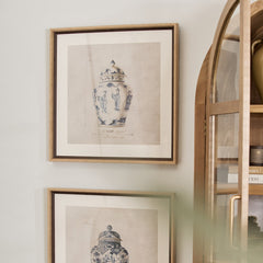 Two framed prints of chinoiserie urns hanging on a wall.