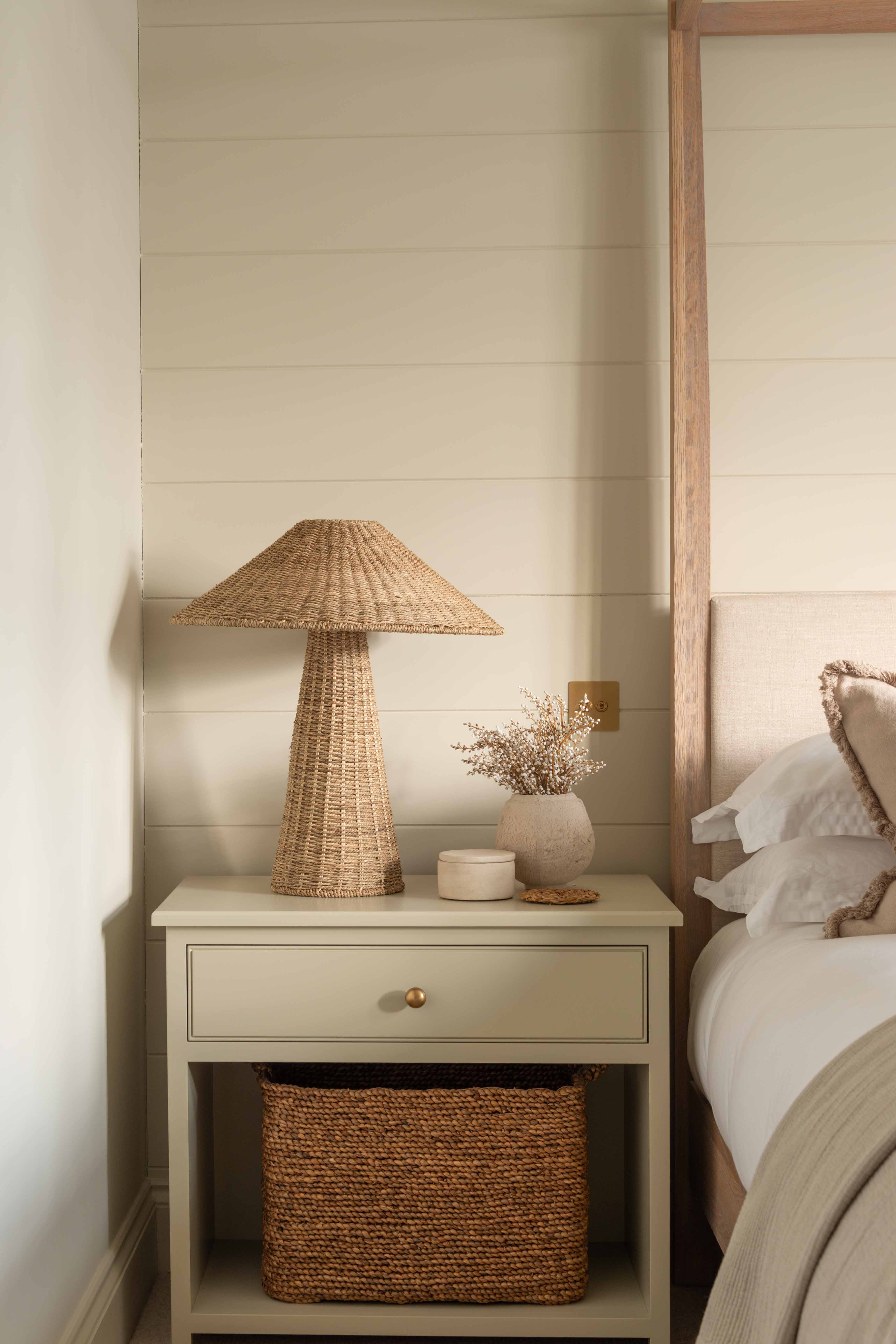 Solara Rattan Table Lamp on bedside table with natural wicker coolie shade in cosy bedroom