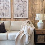 Cosy living room with beige sofa, throw blanket, framed artwork, and side table.