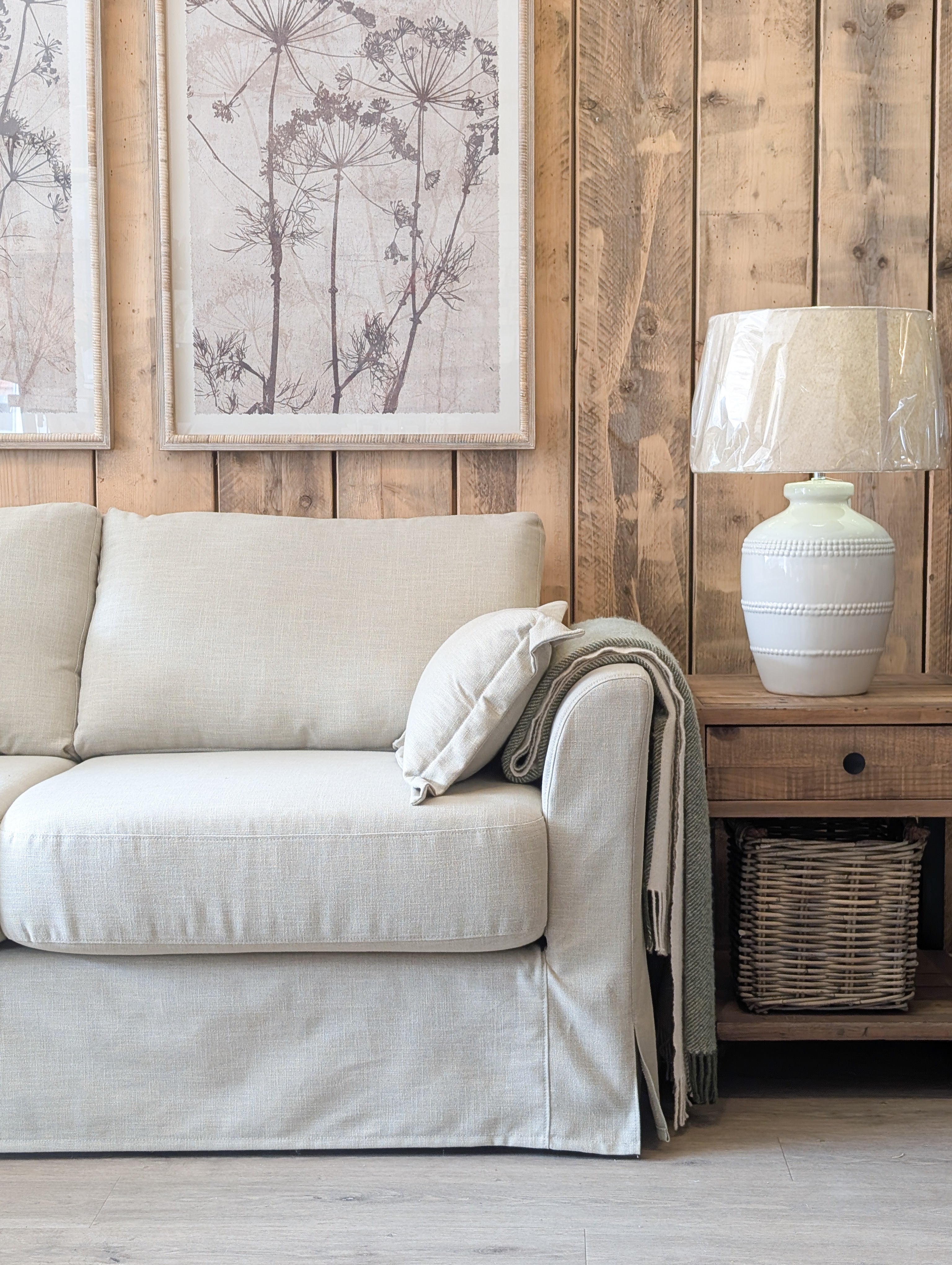 Beige sofa in a living room with wooden wall paneling and a lamp.