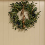 Green wreath with copper bells on a beige wall