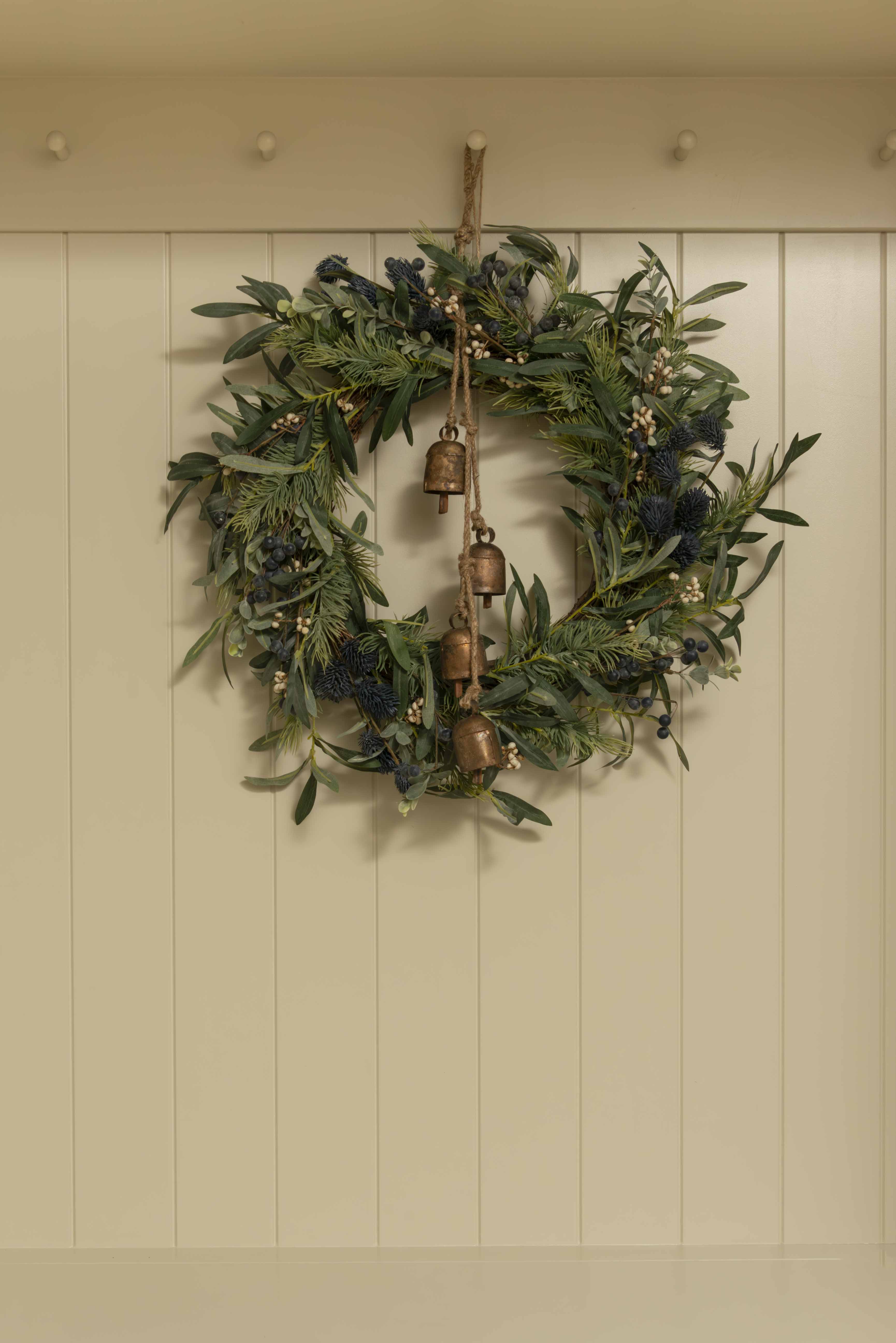 Green wreath with copper bells on a beige wall