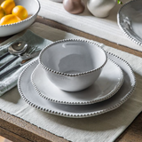 White ceramic dinnerware set on a wooden table with a neutral color scheme.